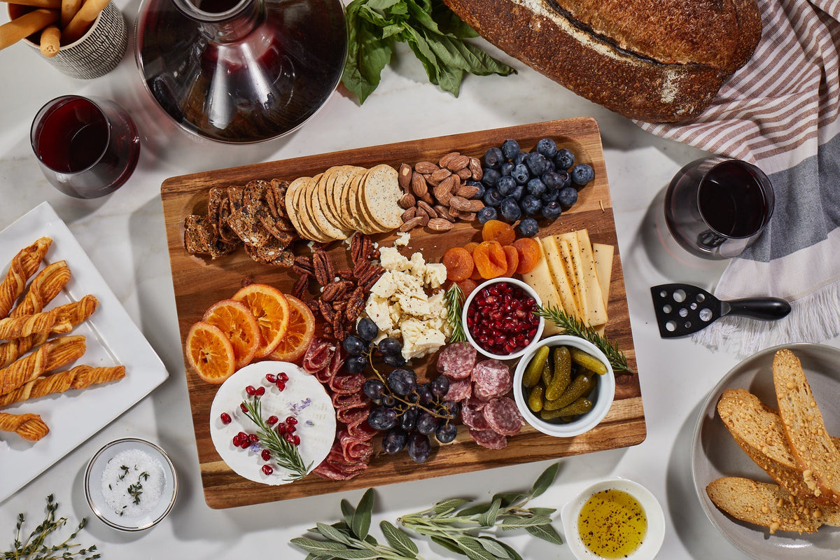 Winsome Acacia Cutting Board with cheeses, salami, crackers, fruit, nuts, and cornichons