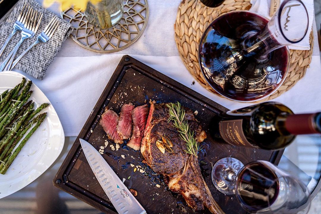 A set tabke with a steak on a cutting board in the centre