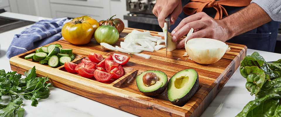 Person preparing vegetables on a Sonder LA wooden cutting board with a kitchen background