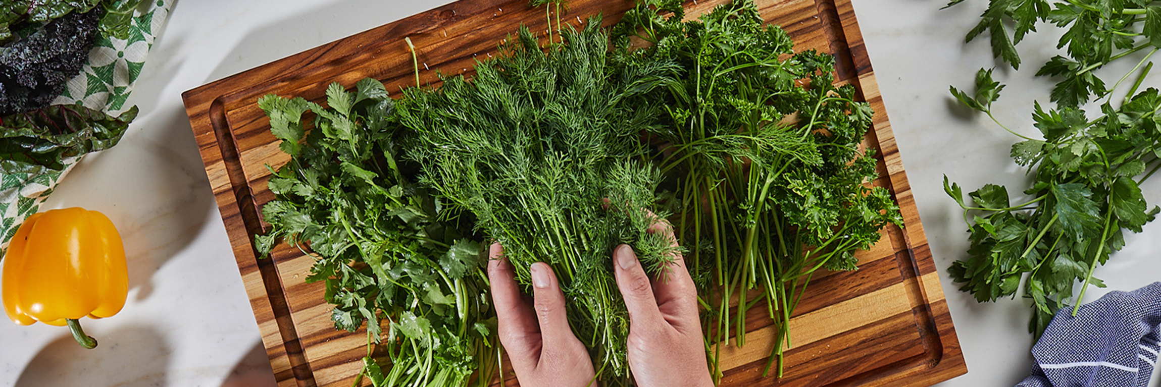 Person preparing herbs on a Sonder LA teak cutting board.