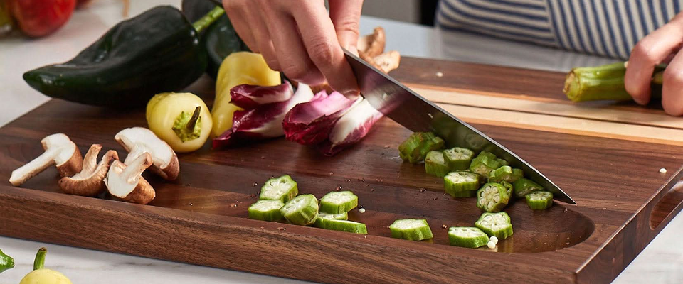 Person chopping vegetables on a Sonder LA wooden cutting board with a knife