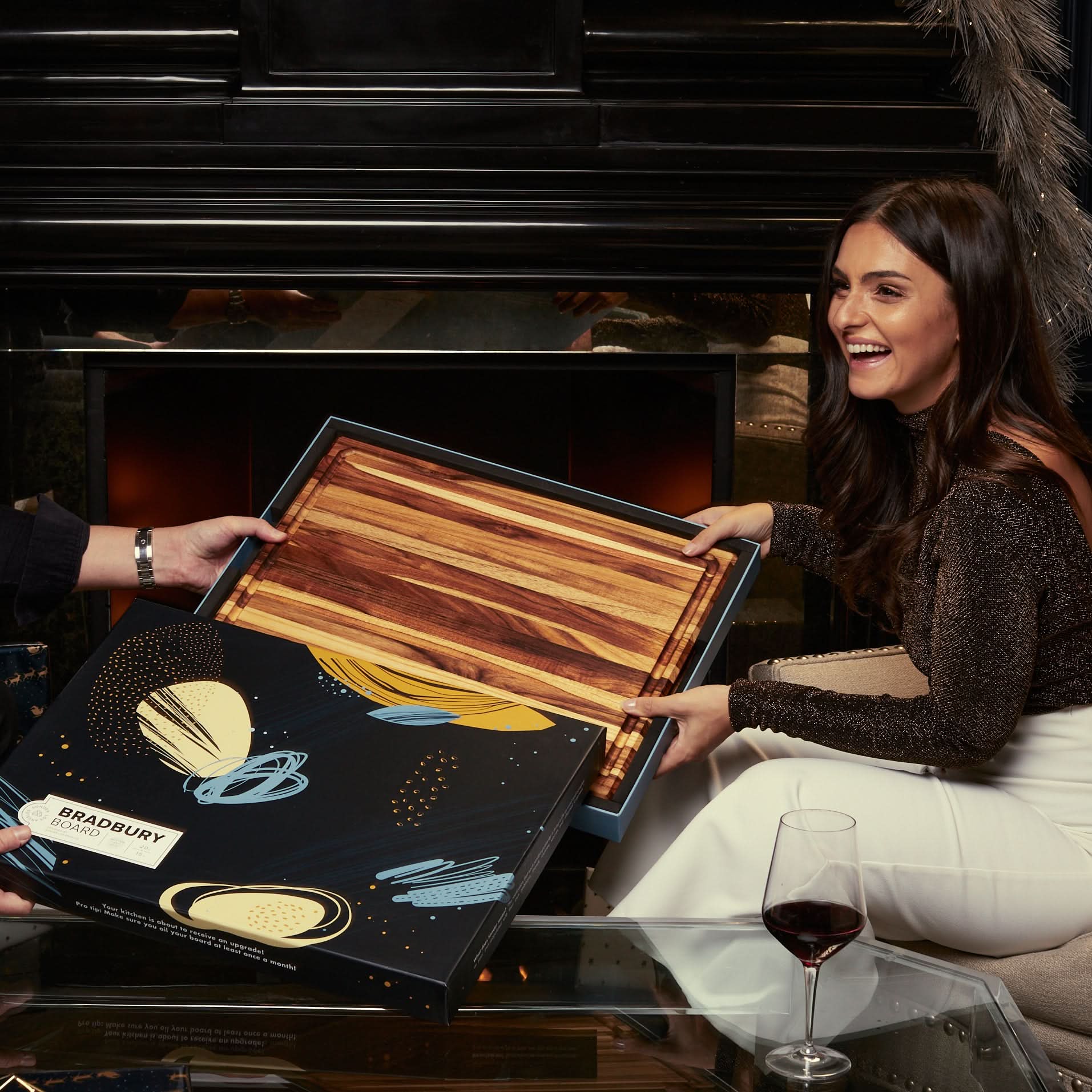 Woman unboxing Sonder Los Angeles Bradbury Extra Large Teak Cutting Board with Gift Box during the holidays