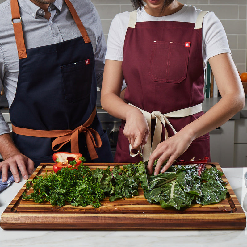 Couple in kitchen chopping swish chard on extra large highland teak wood cutting board by sonder los angeles