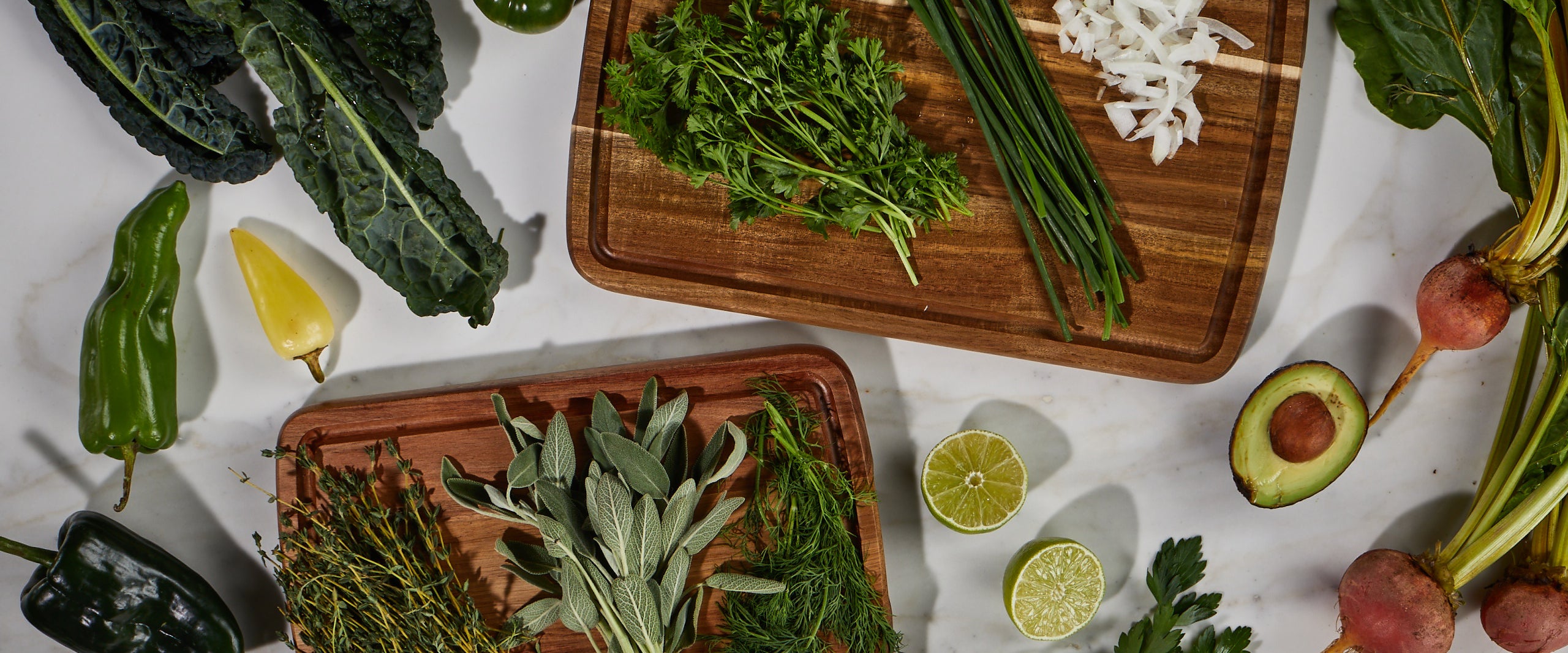 Assorted fresh herbs and greens on Sonder LA Doheny Duo set of cutting boards.