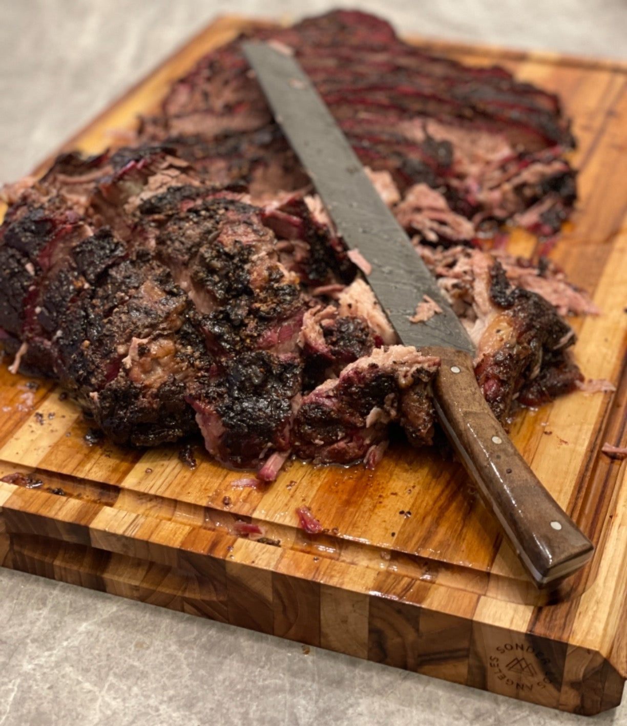Smoked brisket on Sonder LA extra large 23x17 highland teak wood cutting board.