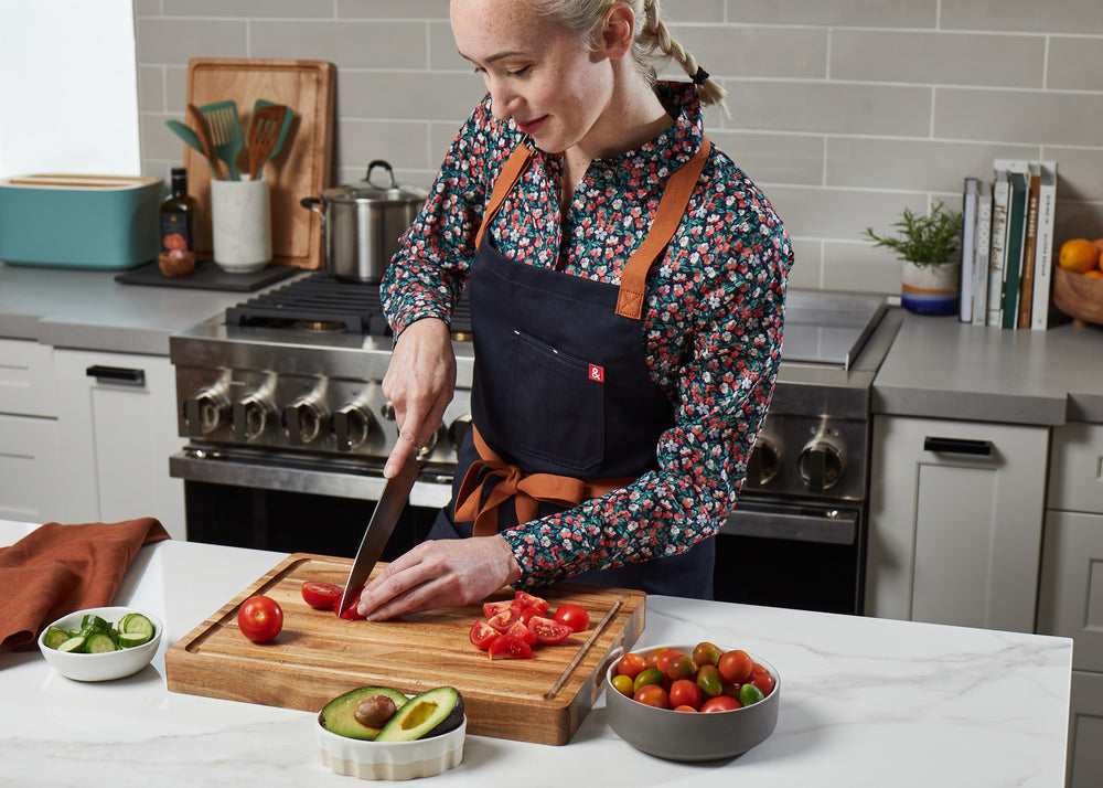 Cute girl with braids and floral shirt in kitchen slicing tomatoes on Sonder Los Angeles Acacia Wood Cutting Board