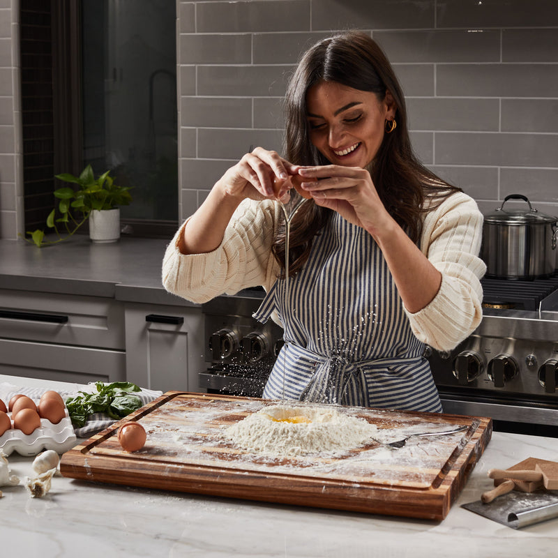 Italian woman in kitchen making pasta from scratch on Sonder LA Highland Extra Large Teak Wood Cutting Board