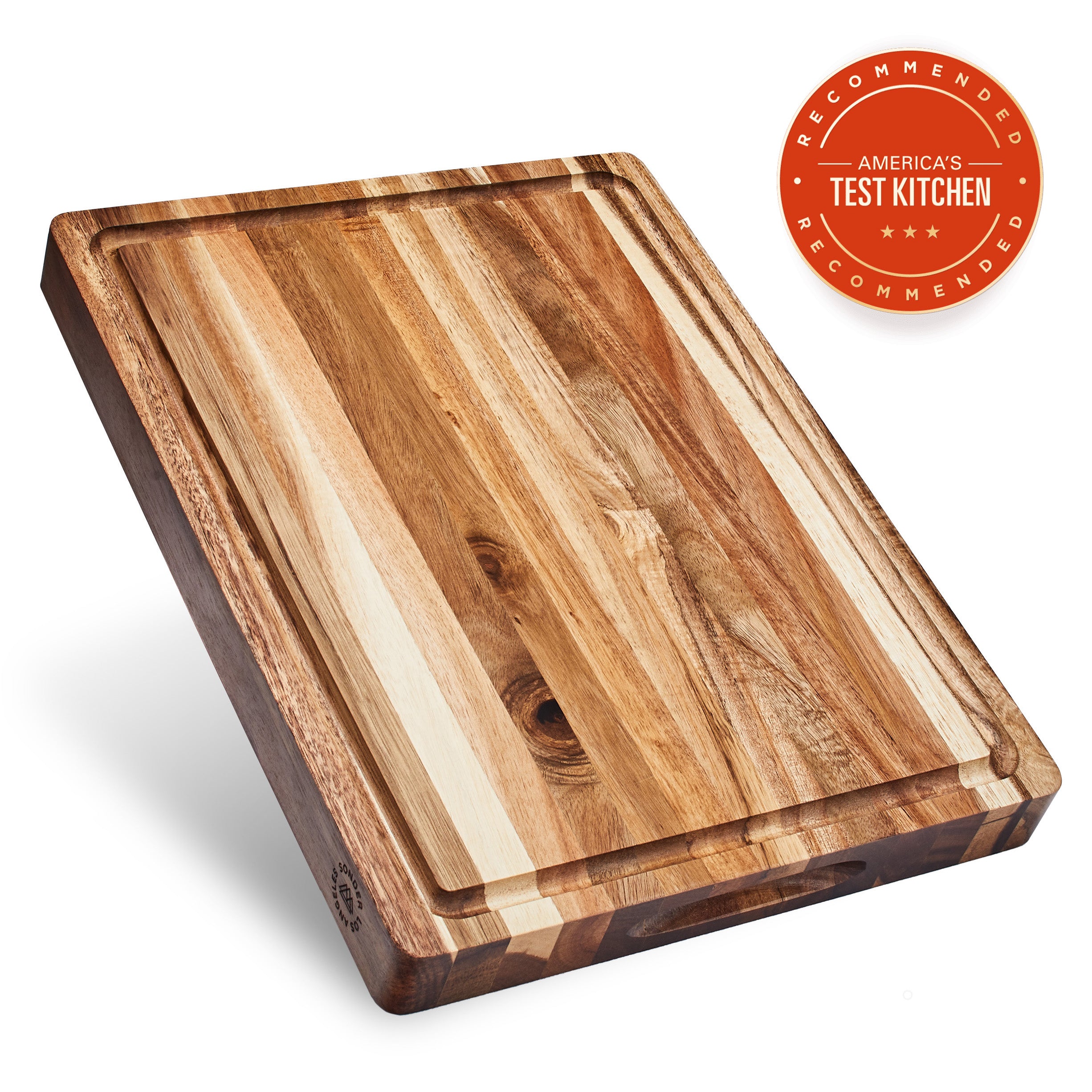 A rectangular acacia wood cutting board with a juice groove, displayed at an angle to show the grain of the wood.