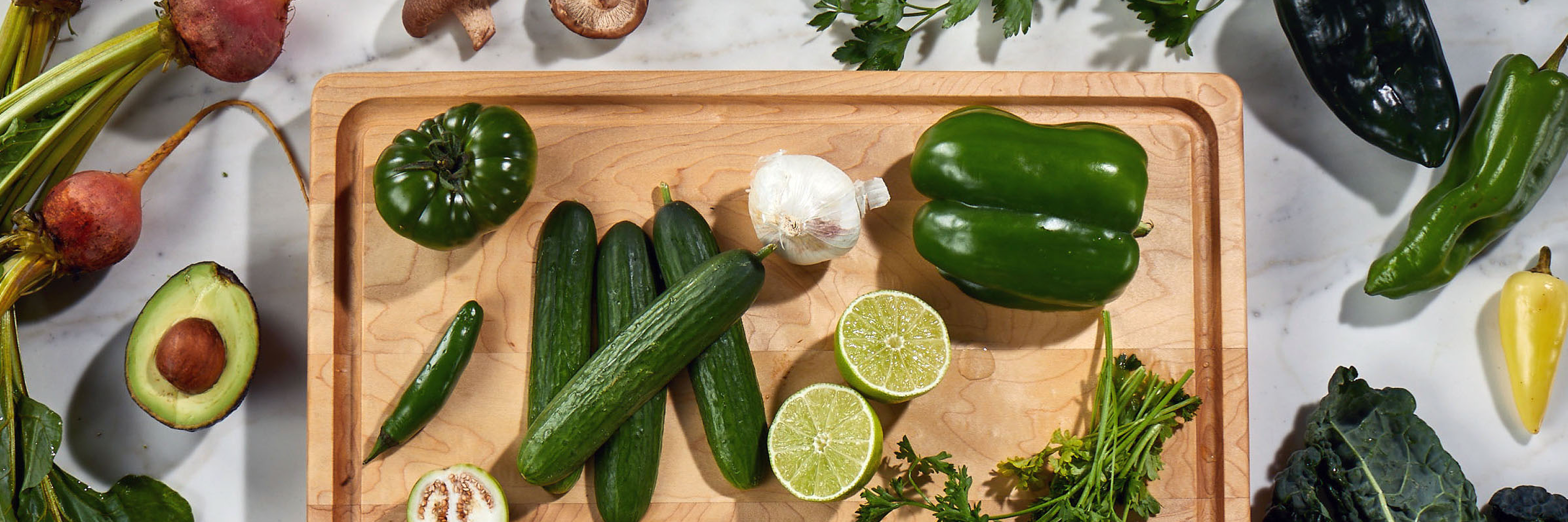 Sonder LA wooden cutting board with green vegetables on a white background