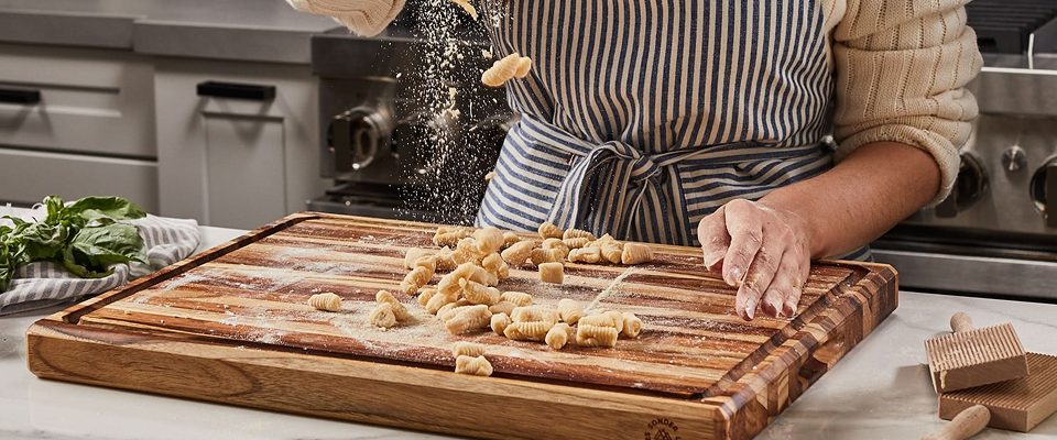 Person making pasta from scratch on a Sonder LA teak cutting board.