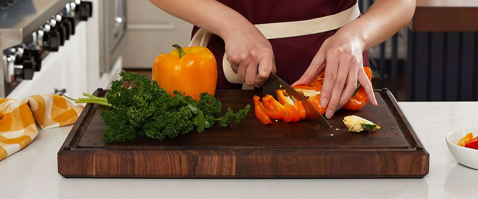 Person cutting vegetables on a wooden Sonder LA cutting board in a kitchen.