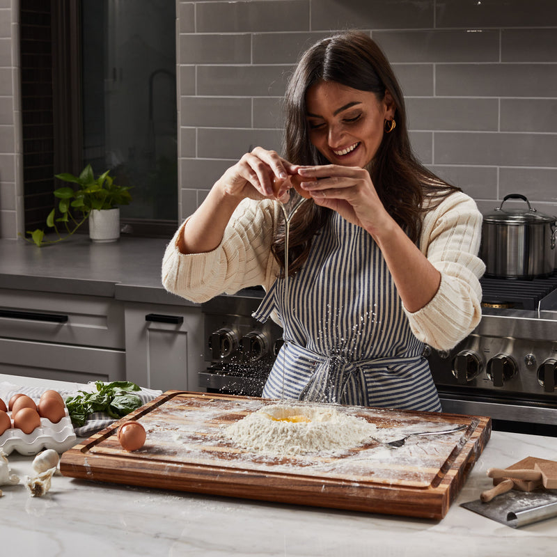 Italian woman in kitchen making pasta from scratch on Sonder Los Angeles Highland XL Teak Wood Cutting Board